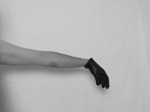 Black and white imagoes an outstretched arm wearing a black leather glove. 